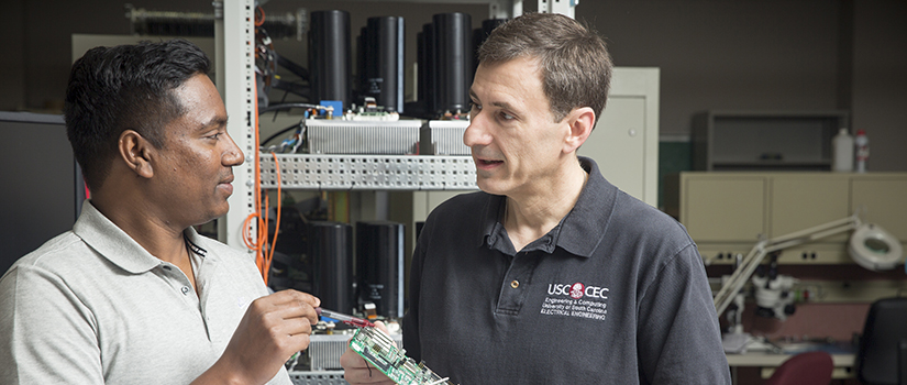 Engineering Faculty looking at a circuit board