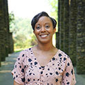Chantelle is pictured from the waist up. She has brown skin, short black hair, brown eyes, and is smiling. 