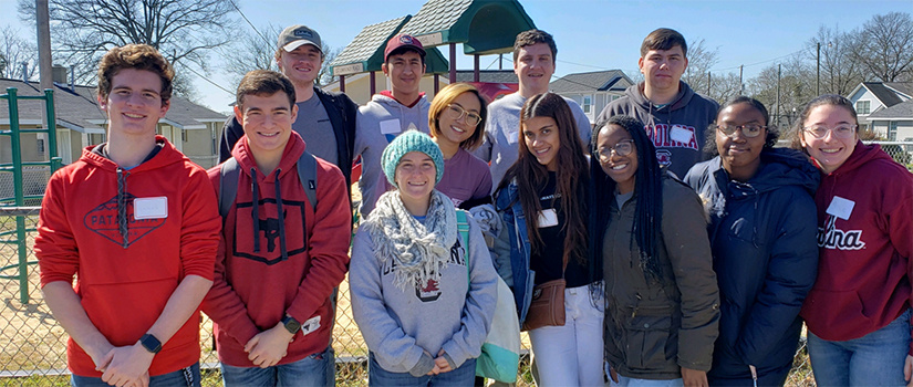 A group of community service ambassadors pose in front of a newly built playground. 