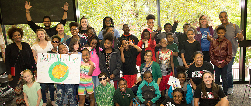 A group of students pose in front of a large window.  