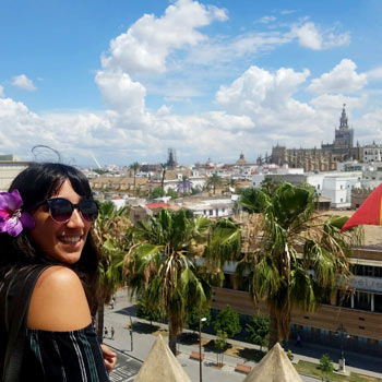 Student studying abroad standing on a balcony overlooking a city.