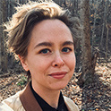 Phot of woman with brown hair and jack on smiling. 