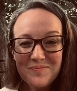 a woman with dark hair and glasses smiles