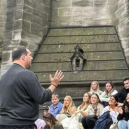 Political Science students being lectured by a professor while on a site visit in the UK