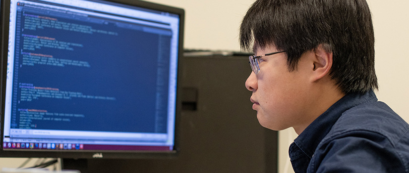 side view of male student looking at computer code