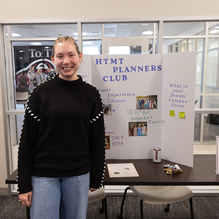 A member of the HTMT Event Planners group poses at a student organization fair