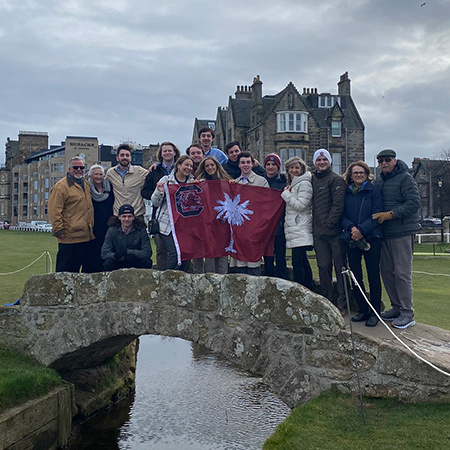 Students stand together on a small bridge while visiting St Andrews Links in Scotland.