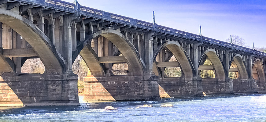 photo of a bridge over a river with blue sky in the background