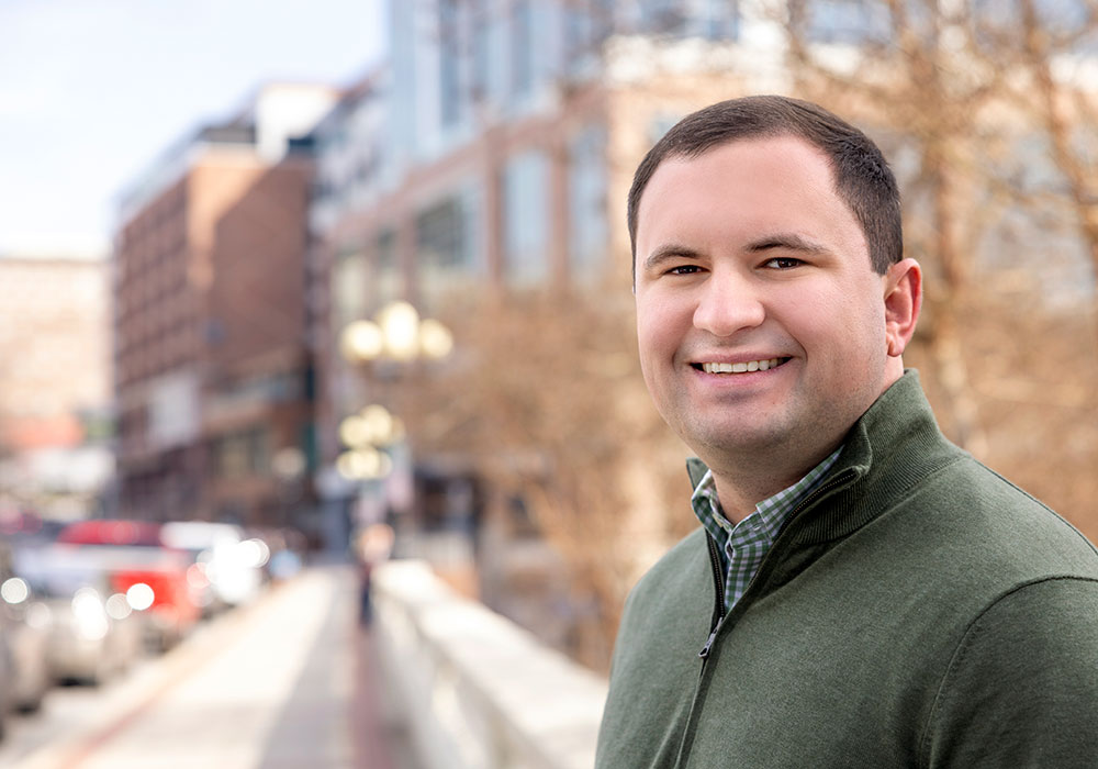 Ross Lordo smiles in front of blurred out Downtown Greenville buildings