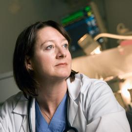 Robin Dail in lab coat in front of NICU incubator