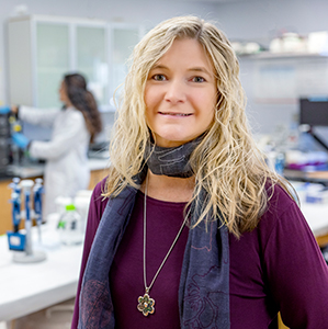 Melissa Moss stands in front of students working in her lab. 