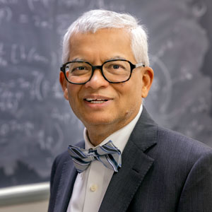 A portrait of Timir Datta with a chalky blackboard in the background.