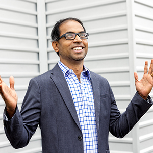 Mani Sockalingam stands in front a building.