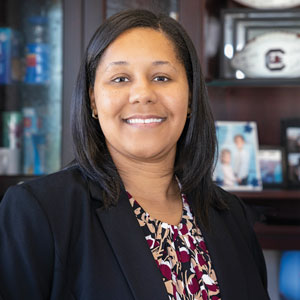 Maria Hickman stands and smiles for the camera in her office.