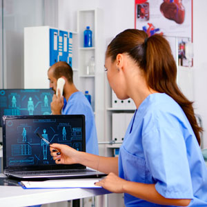 a health care worker looks at a computer screen with equipment in the background