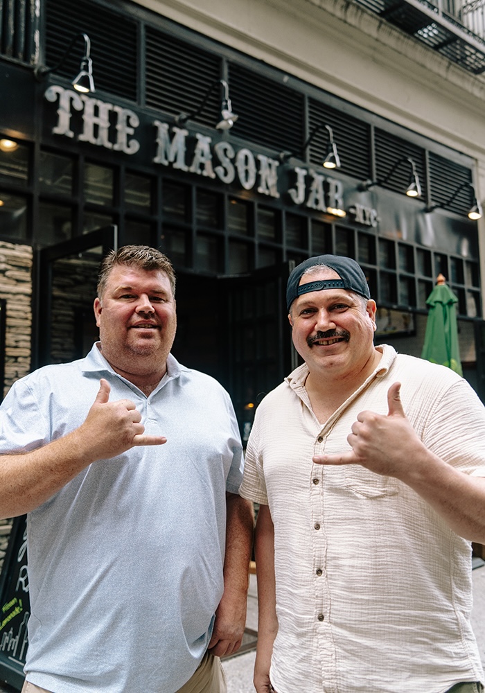 Co-owners of the Mason Jar pose in front of the Mason Jar Bar in NYC.