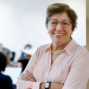 Gail V. Barnes stands in the doorway with students playing string instruments behind her