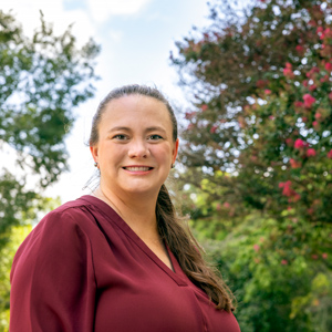 woman stands outside with trees in the background