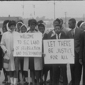 Civil rights protesters stand with signs reading 