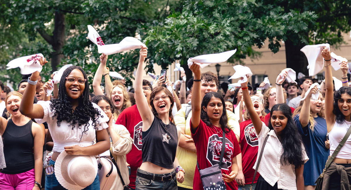 a group of people stand together waving white towels